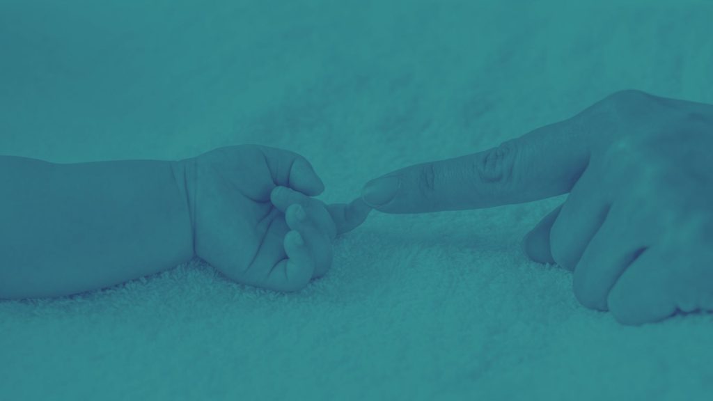 Parent touching newborn's hand